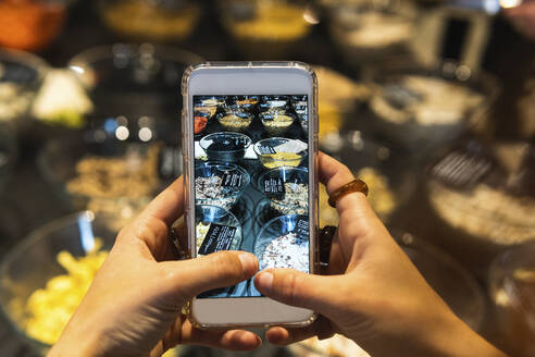 Junge Frau fotografiert Lebensmittel im Supermarkt - PNAF01618