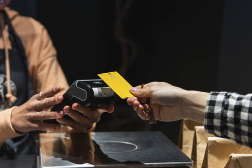 Weibliche Kundin gibt Kreditkarte an Besitzer im Supermarkt - PNAF01635