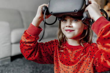 Lächelndes Mädchen trägt Virtual-Reality-Simulator zu Hause - OGF01032