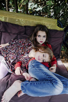 Niedliche Schwestern entspannen sich auf einer Liege im Hinterhof - OGF01034