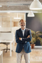 Senior male entrepreneur standing with arms crossed in office - GUSF05762