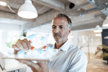 Male entrepreneur holding molecule model on digital tablet in office - GUSF05771