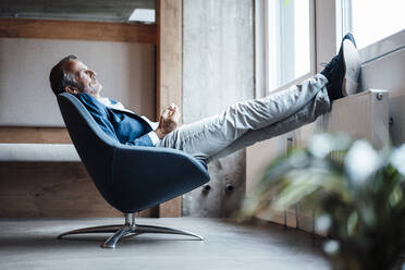 Thoughtful businessman looking away while sitting in office - GUSF05784