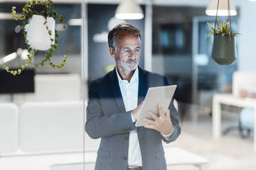 Geschäftsmann, der ein digitales Tablet bei der Arbeit im Büro benutzt - GUSF05795