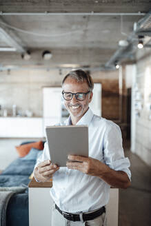 Männlicher Berufstätiger, der im Stehen im Büro ein digitales Tablet benutzt - GUSF05822