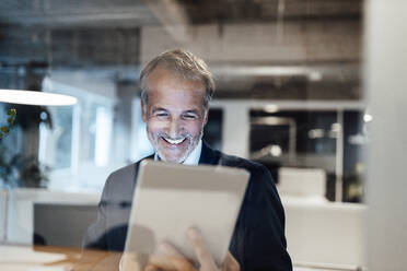 Ein älterer männlicher Unternehmer benutzt ein digitales Tablet im Büro - GUSF05849