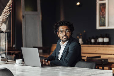 Mature businessman using laptop while sitting in cafe - GUSF05920