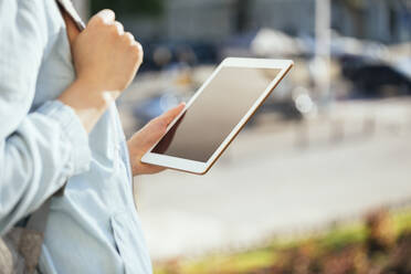Mittlere erwachsene Frau hält digitales Tablet im Freien - OYF00374
