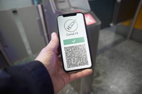 Mann zeigt digitalen COVID-19-Impfpass auf dem Smartphone am Flughafen - PSBHF00018