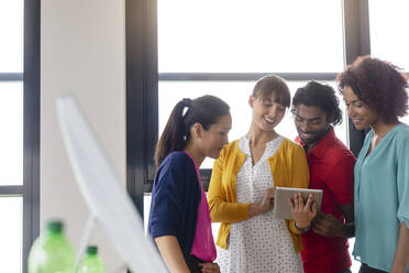 Male and female business people discussing over digital tablet in library - BMOF00797