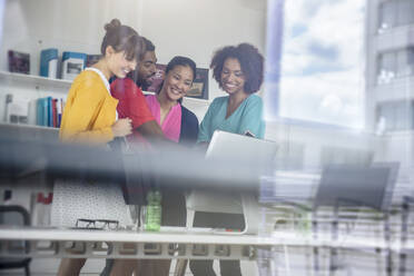 Man explaining female colleagues over desktop PC in library seen through glass - BMOF00802