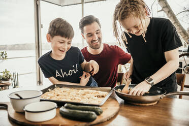 Glückliche Jungen bereiten mit ihrem Vater in der Küche eines Hausbootes Essen zu - MJRF00571