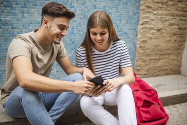 Ehepaar benutzt Mobiltelefon auf dem Gehweg - GRCF00707