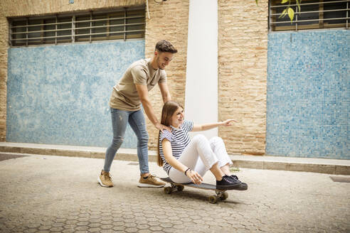 Fröhliches Paar spielt mit Skateboard auf dem Fußweg - GRCF00710