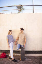 Romantic couple holding hands while leaning on wall - GRCF00718