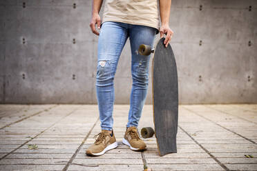 Junger Mann mit Skateboard auf dem Gehweg stehend - GRCF00722