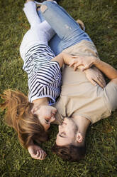 Couple romancing while lying on lawn - GRCF00727