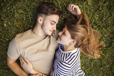 Smiling romantic couple lying on grass - GRCF00728