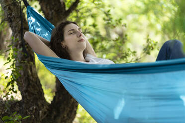 Young woman with eyes closed relaxing on hammock - SBOF03849