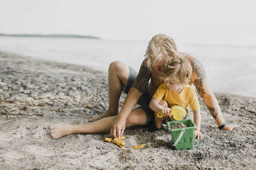 Vater und Sohn spielen mit Sand am Strand - HWHF00022