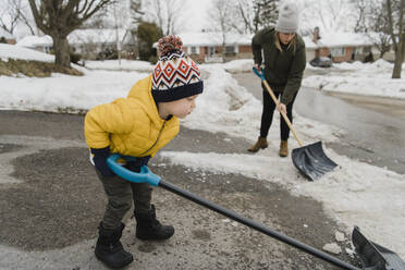 Sohn hilft Mutter beim Schneeschaufeln in der Einfahrt - HWHF00033