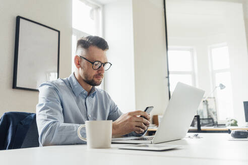 Geschäftsmann benutzt Mobiltelefon am Arbeitsplatz - VPIF04057