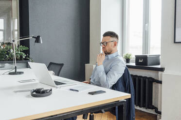 Male professional with hand on chin contemplating in office - VPIF04064