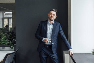 Mid adult male entrepreneur with eyeglasses standing at office - VPIF04103