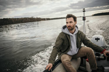 Hübscher Mann sitzt in einem Boot am Seddinsee - MJRF00591