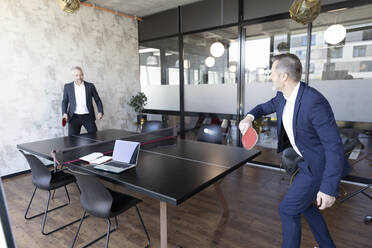 Businessmen playing table tennis at office - FKF04161