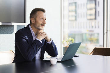 Male professional contemplating while sitting at desk in office - FKF04167