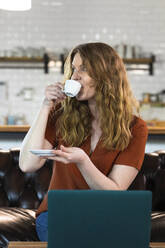 Geschäftsfrau schaut weg, während sie in der Büro-Cafeteria Kaffee trinkt - FKF04170