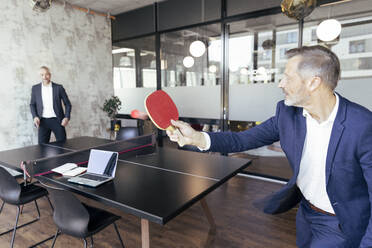 Männliche Fachkräfte spielen Tischtennis im Büro - FKF04257