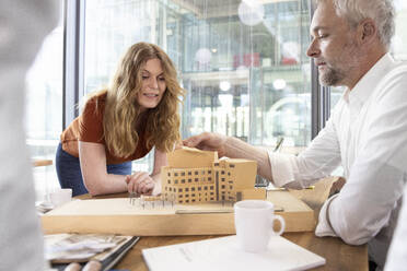 Männliche und weibliche Architekten diskutieren über ein Architekturmodell im Büro - FKF04305