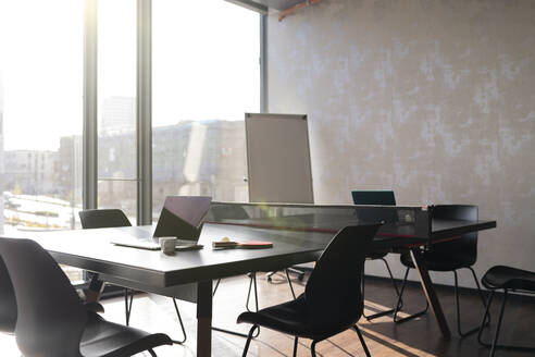 Empty chairs and laptop at tennis table in office - FKF04339