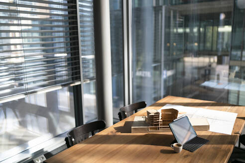 Architekturmodell mit Blaupause und Laptop auf einem Tisch im Büro - FKF04342