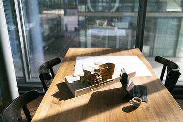 Sonnenlicht fällt auf Blaupause und Architekturmodell im Büro - FKF04344