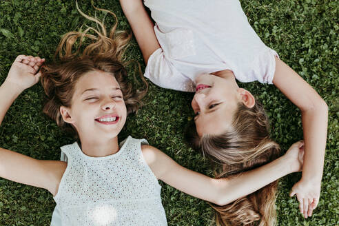 Glückliche Mädchen liegen im Sommer im Gras - EBBF03746