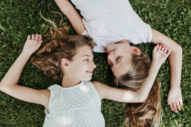 Smiling girls relaxing on grass in summer - EBBF03747