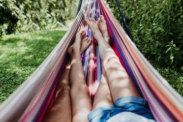 Girls lying in hammock on sunny day - EBBF03765