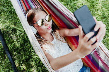 Girl wearing sunglasses puckering while taking selfie in hammock - EBBF03776