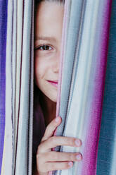 Smiling girl peeking through hammock - EBBF03777