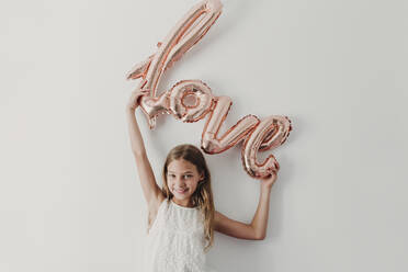 Smiling girl enjoying with shiny love balloon - EBBF03782