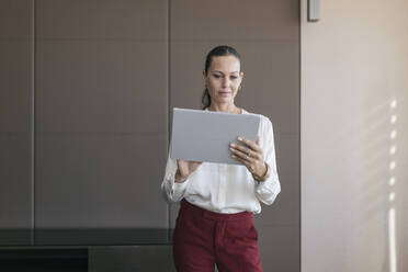 Reife Geschäftsfrau, die im Stehen im Büro ein digitales Tablet benutzt - JRVF00792