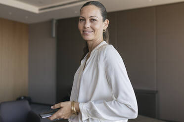Lächelnde weibliche Fachkraft mit Smartphone im Büro - JRVF00803