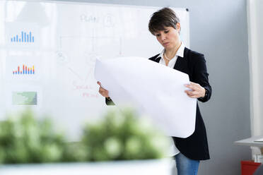 Businesswoman analyzing business plan in office - GIOF12688