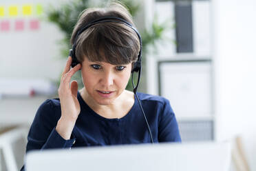 Geschäftsfrau mit Headset bei der Arbeit im Büro - GIOF12699