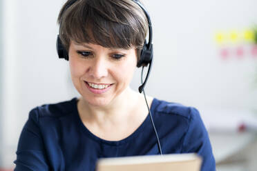 Lächelnde Geschäftsfrau mit Headset im Büro - GIOF12702