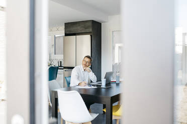 Businessman contemplating at table seen through door at home - JRFF05146