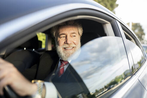 Lächelnder Geschäftsmann schaut durch ein Autofenster - JCCMF02610